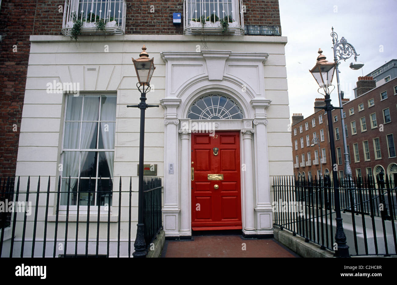 Façade d'une maison géorgienne dans Merrion Square. Il a une porte rouge, balustrades et lampadaires de chaque côté. Square au début 1800 Banque D'Images