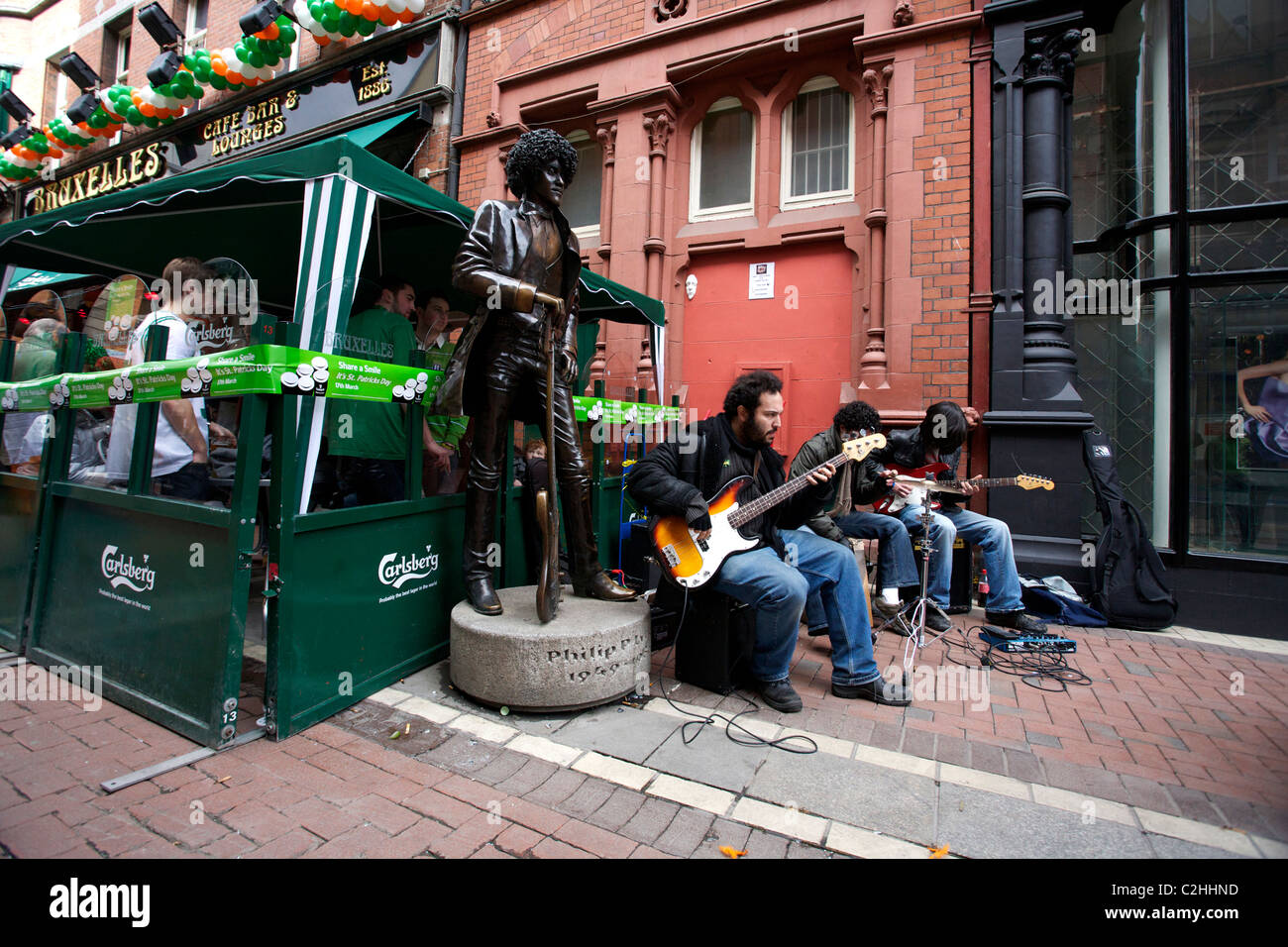 Les joueurs de musique à côté de la statue de Phil Lynott musicien du groupe Thin Lizzy. St Patricks Day in Dublin Ireland Banque D'Images