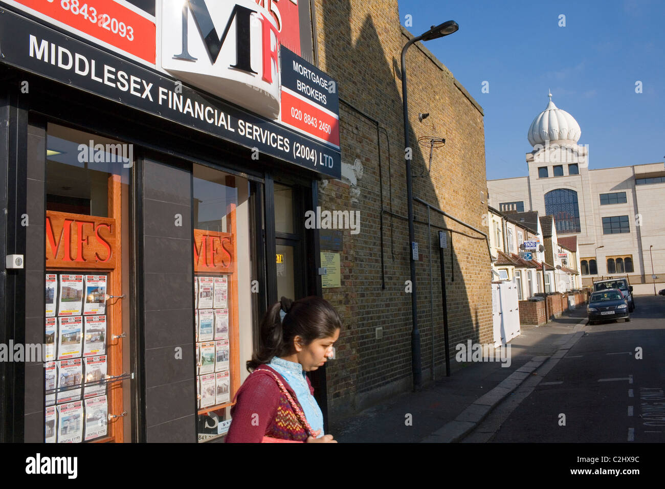 Une femme traverse la route près d'un temple sikh à Southall. Banque D'Images