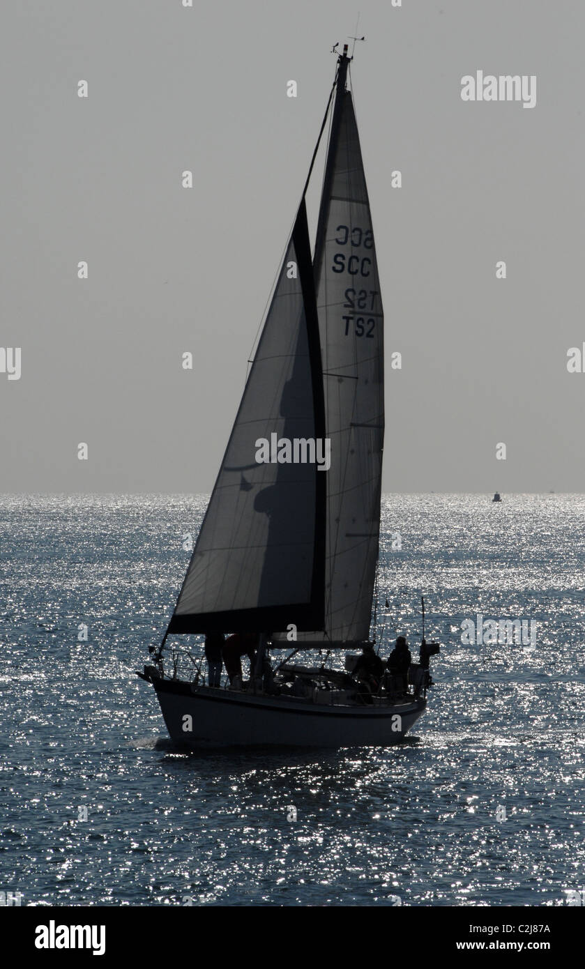 Un yacht à voile plein contre une mer étincelante. Contre jour de l'éclairage. Banque D'Images