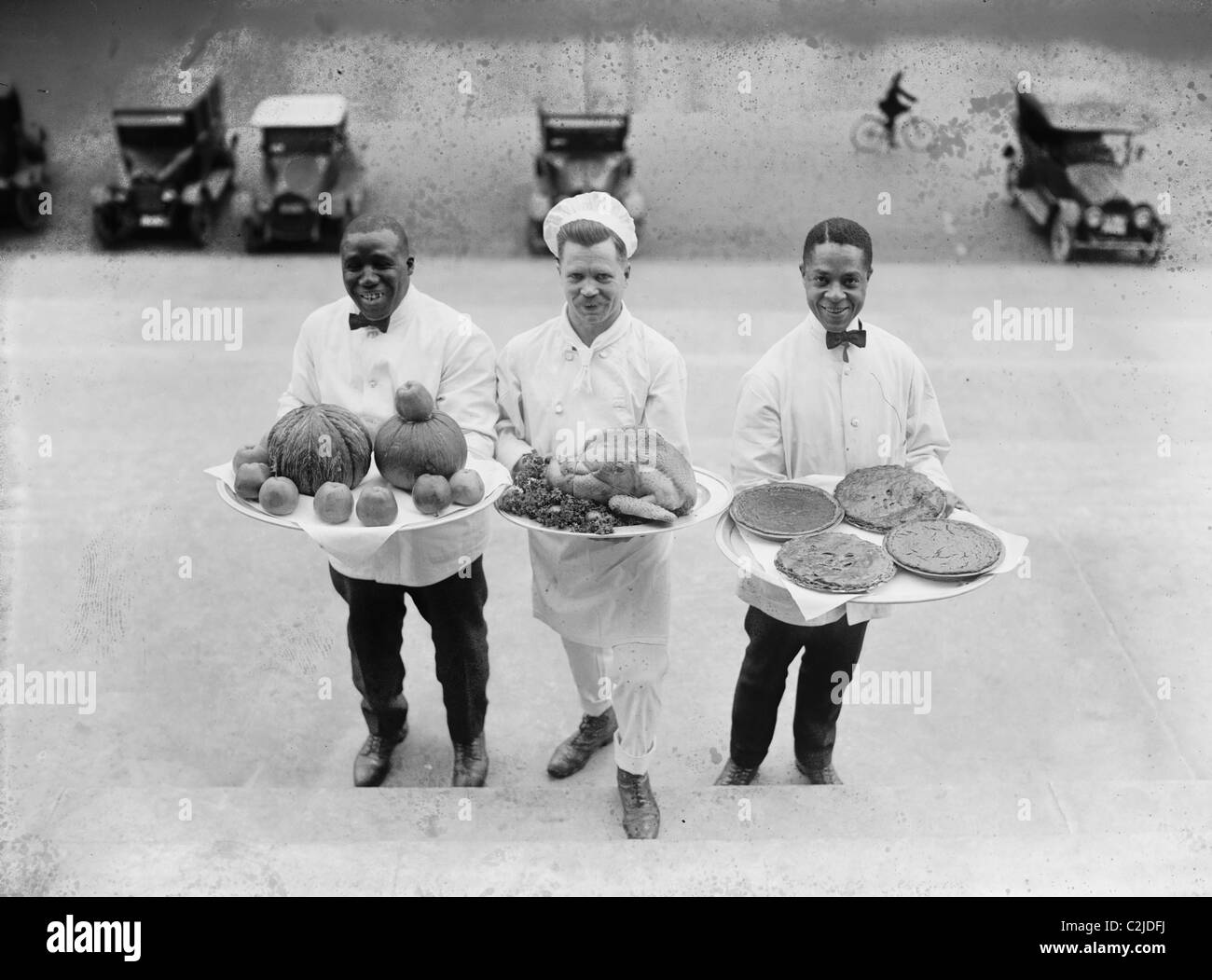 Trois chefs se tenir sur fond d'une ligne d'étapes et de retarder l'action de grâce les plateaux de tartes, de pommes et d'une Turquie Banque D'Images