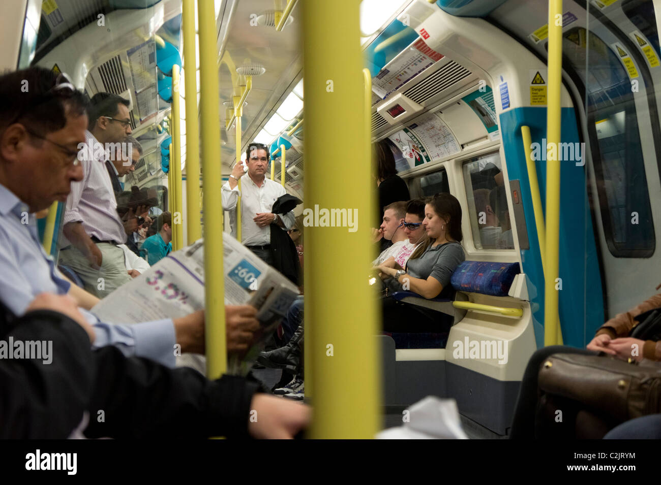 Les passagers de lire les journaux dans un Londres Underground tube train, Londres, Angleterre, Royaume-Uni Banque D'Images