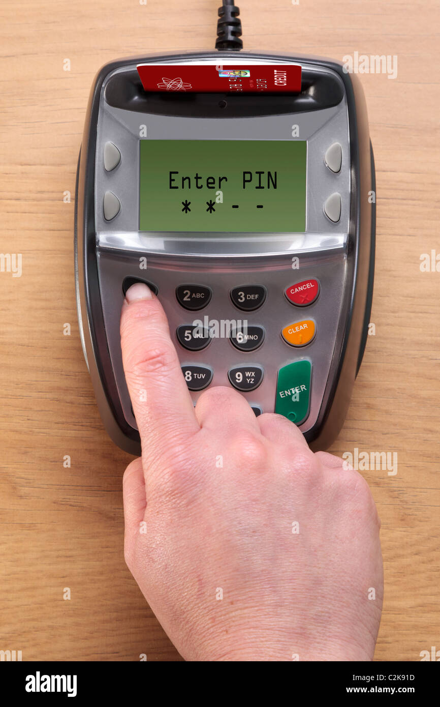 Photo d'une main de femme tapant son numéro dans une puce et NIP terminal de carte de crédit, la carte dans la machine est une maquette. Banque D'Images
