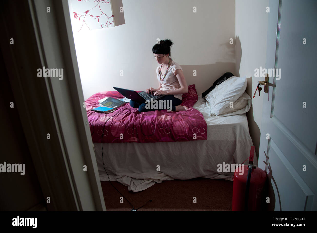 Une jeune femme fille UK university étudiant travaillant sur son ordinateur portable dans sa chambre à coucher à la maison, MySpace Facebook social network Banque D'Images