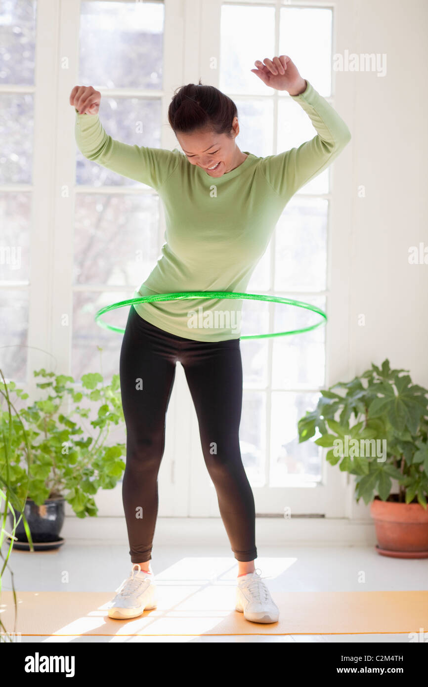 Smiling Asian woman exercising with hula hoop Banque D'Images