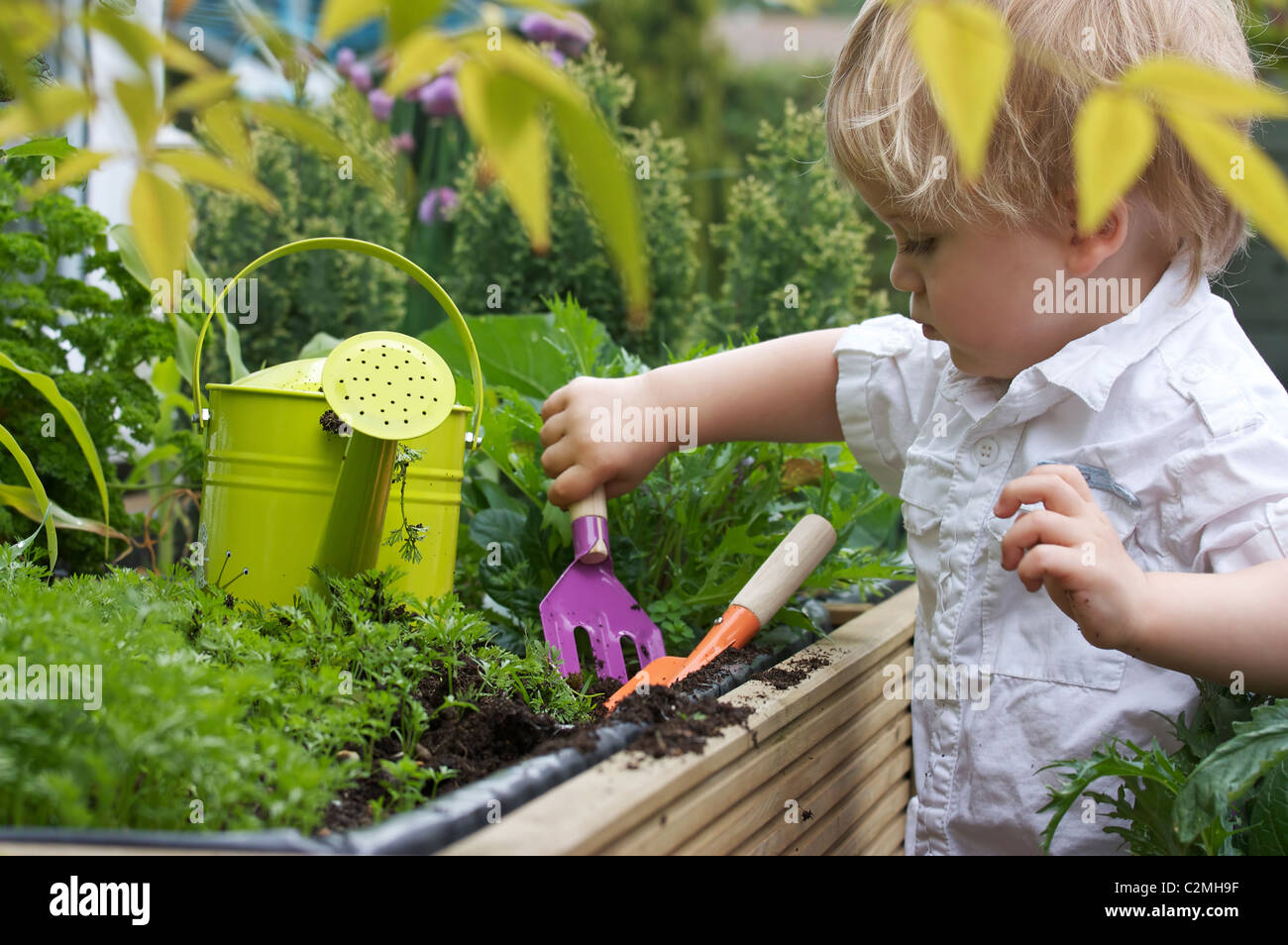 Un enfant en extérieur avec des outils de jardinage bébé Banque D'Images