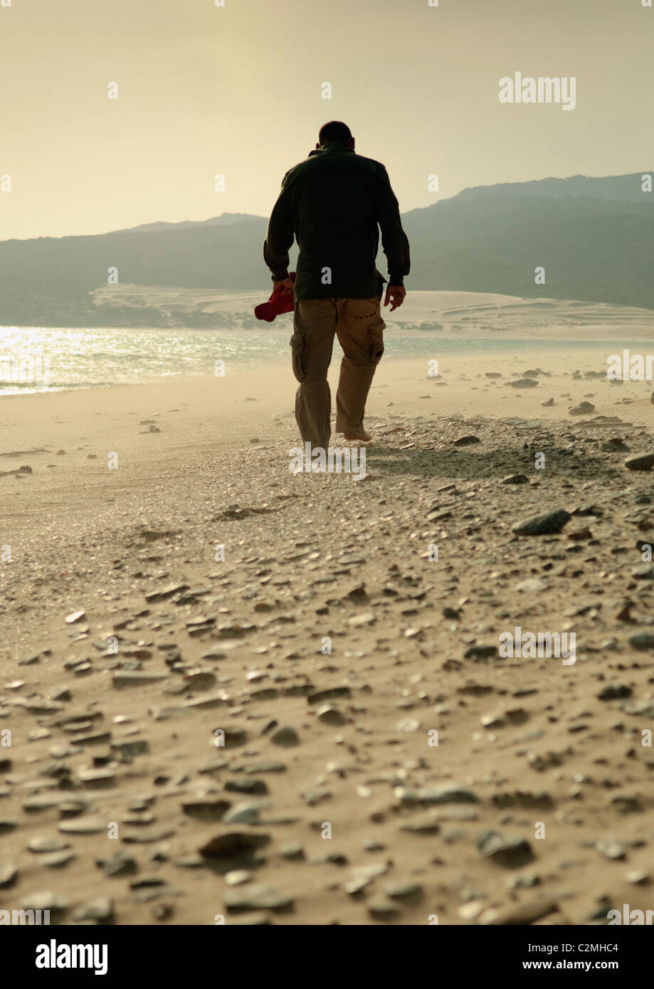 Homme marchant sur une plage rocheuse Banque D'Images