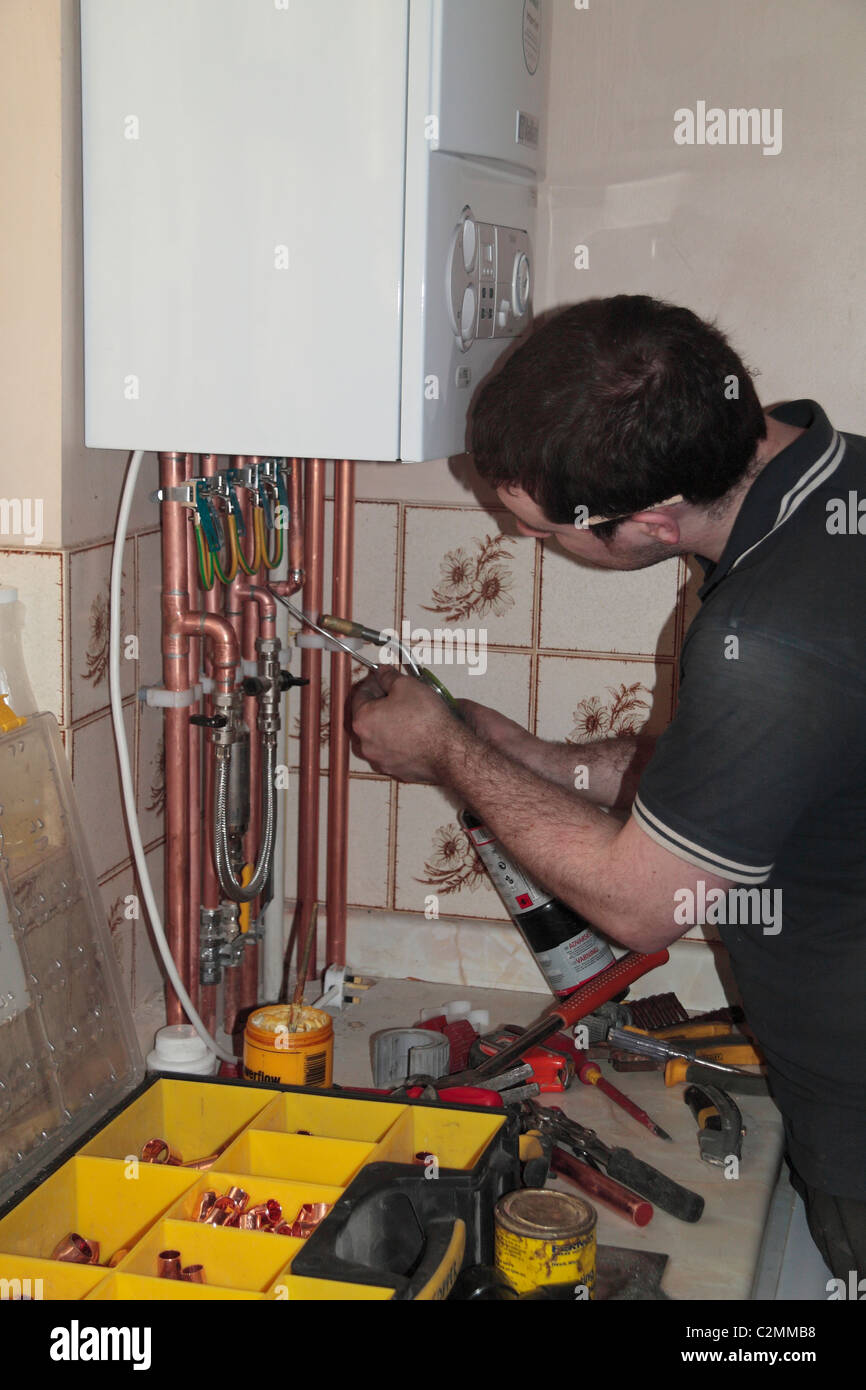 Un ingénieur de chauffage un tuyau à souder lors de l'installation d'une nouvelle chaudière à condensation de marque vaillant dans un immeuble résidentiel. Banque D'Images