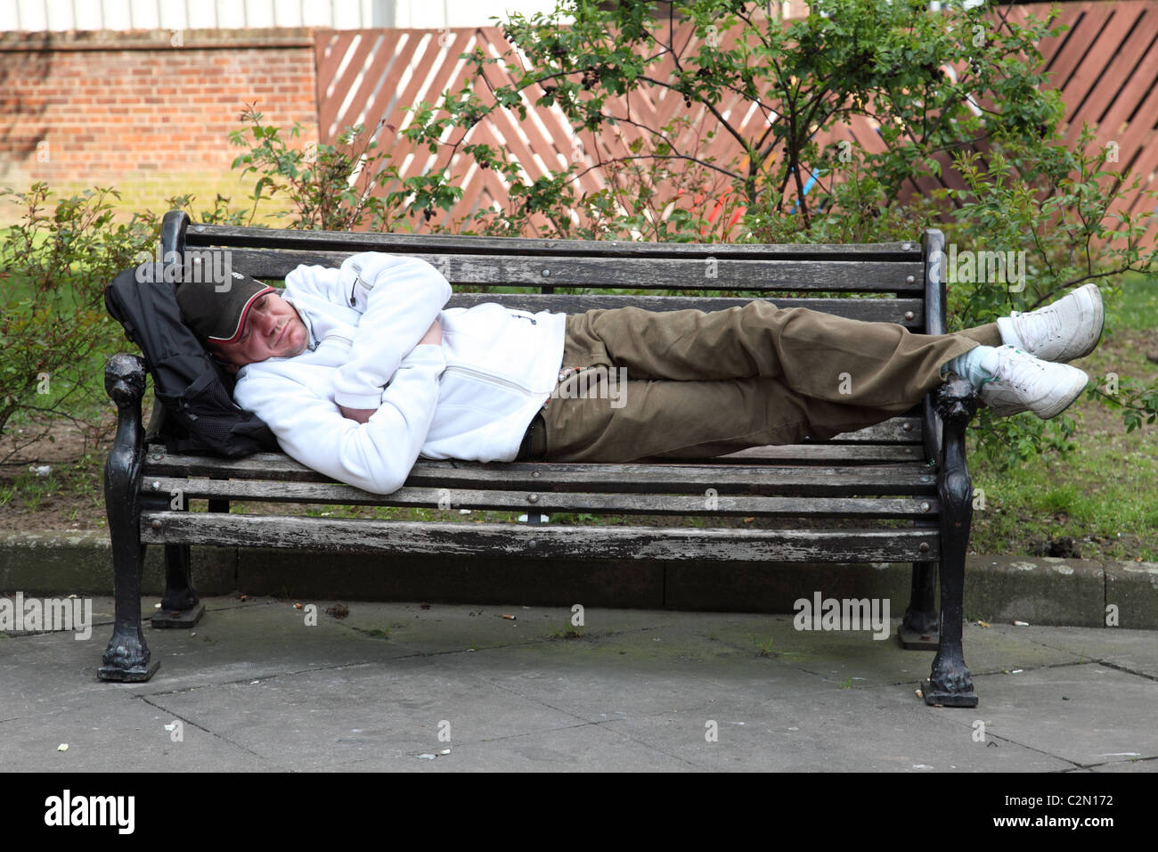 Un homme endormi sur un banc dans une ville du Royaume-Uni. Banque D'Images