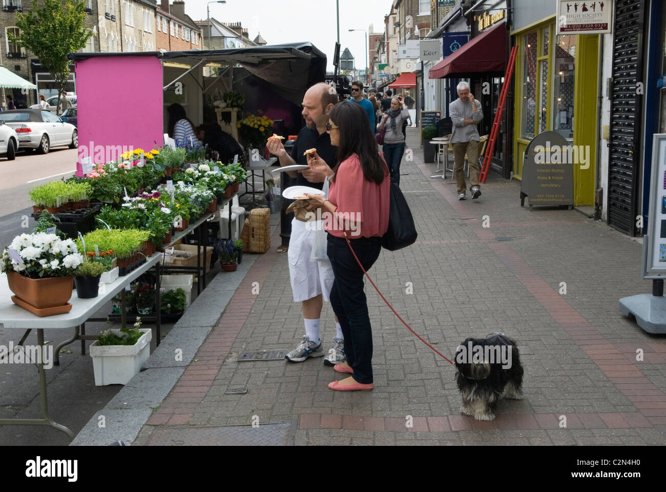 Manger dans la rue en pensant acheter des plantes, un couple avec chien de compagnie. Northcote Road, Clapham, South West London Borough of Wandsworth. SW11 ANNÉES 2011 2010 ROYAUME-UNI HOMER SYKES Banque D'Images