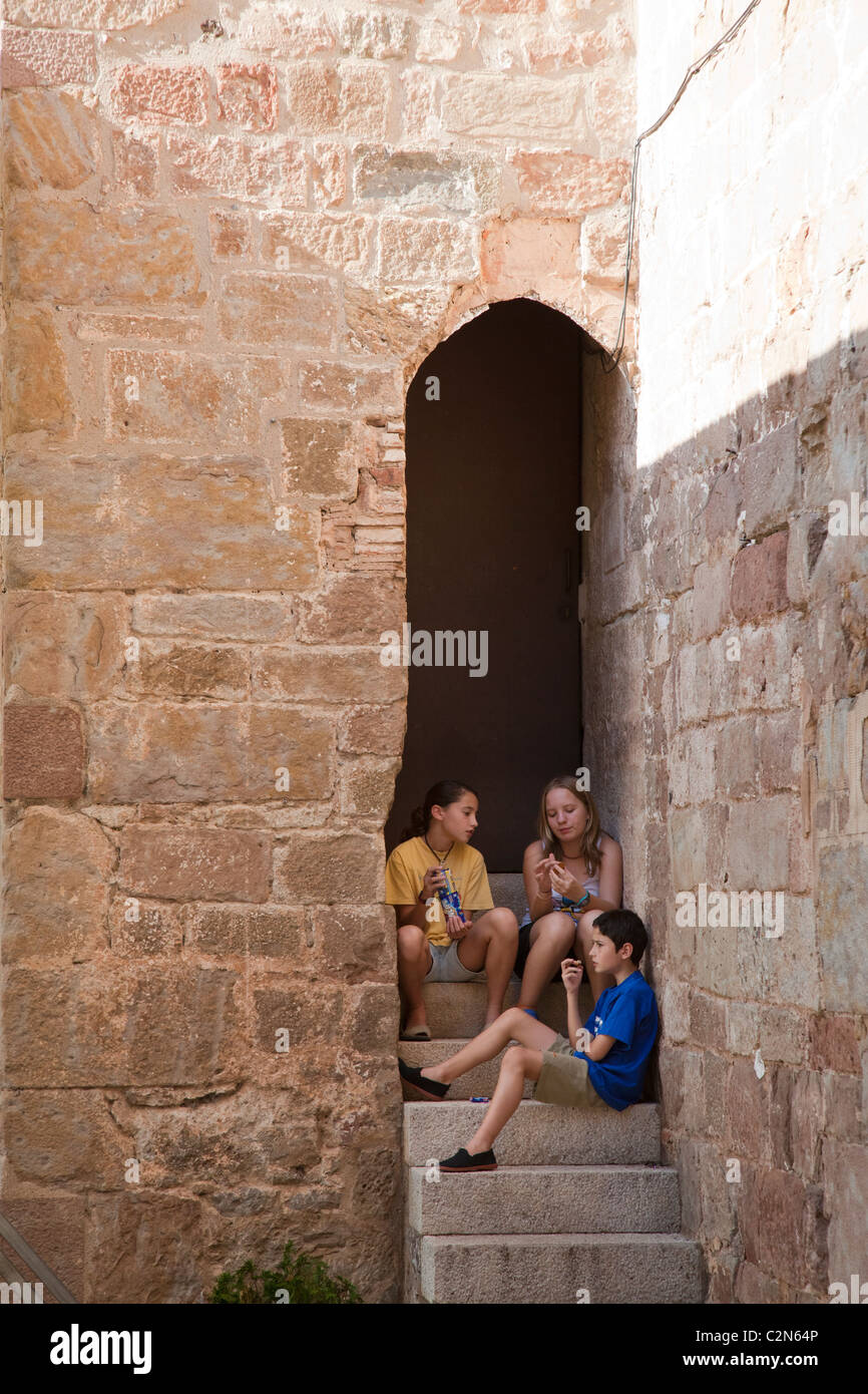 Trois enfants assis à l'ombre sur les mesures à Santa Pau Garrotxa Catalogne Espagne Banque D'Images