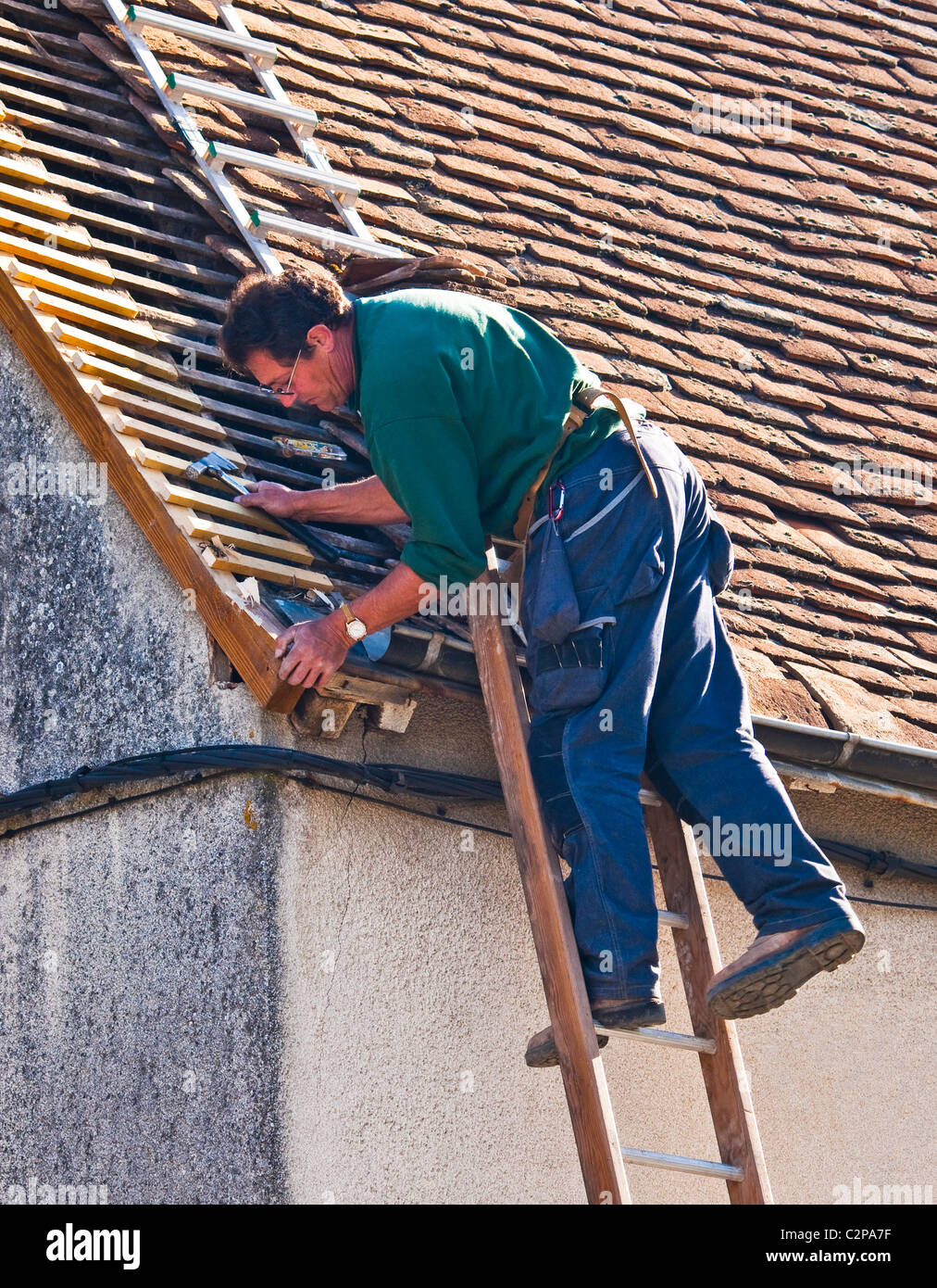 Workman sur l'échelle la réparation de vieux bois avec toit en bois nouveau - France. Banque D'Images