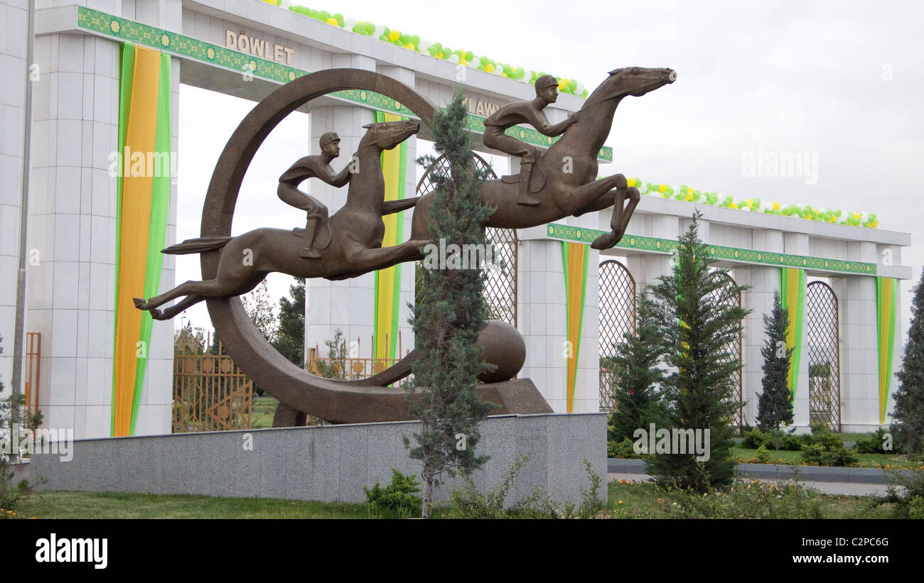 La sculpture des courses de chevaux en face des portes de l'Hippodrome de l'État à Achgabat, au Turkménistan. Banque D'Images