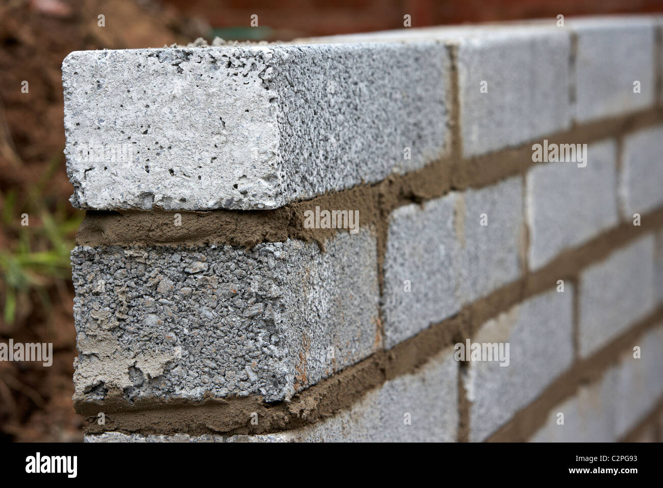 Mur de maçonnerie nouvellement posées avec la moitié en parpaings de ciment construction d'un mur de soutènement en bloc au Royaume-Uni Banque D'Images