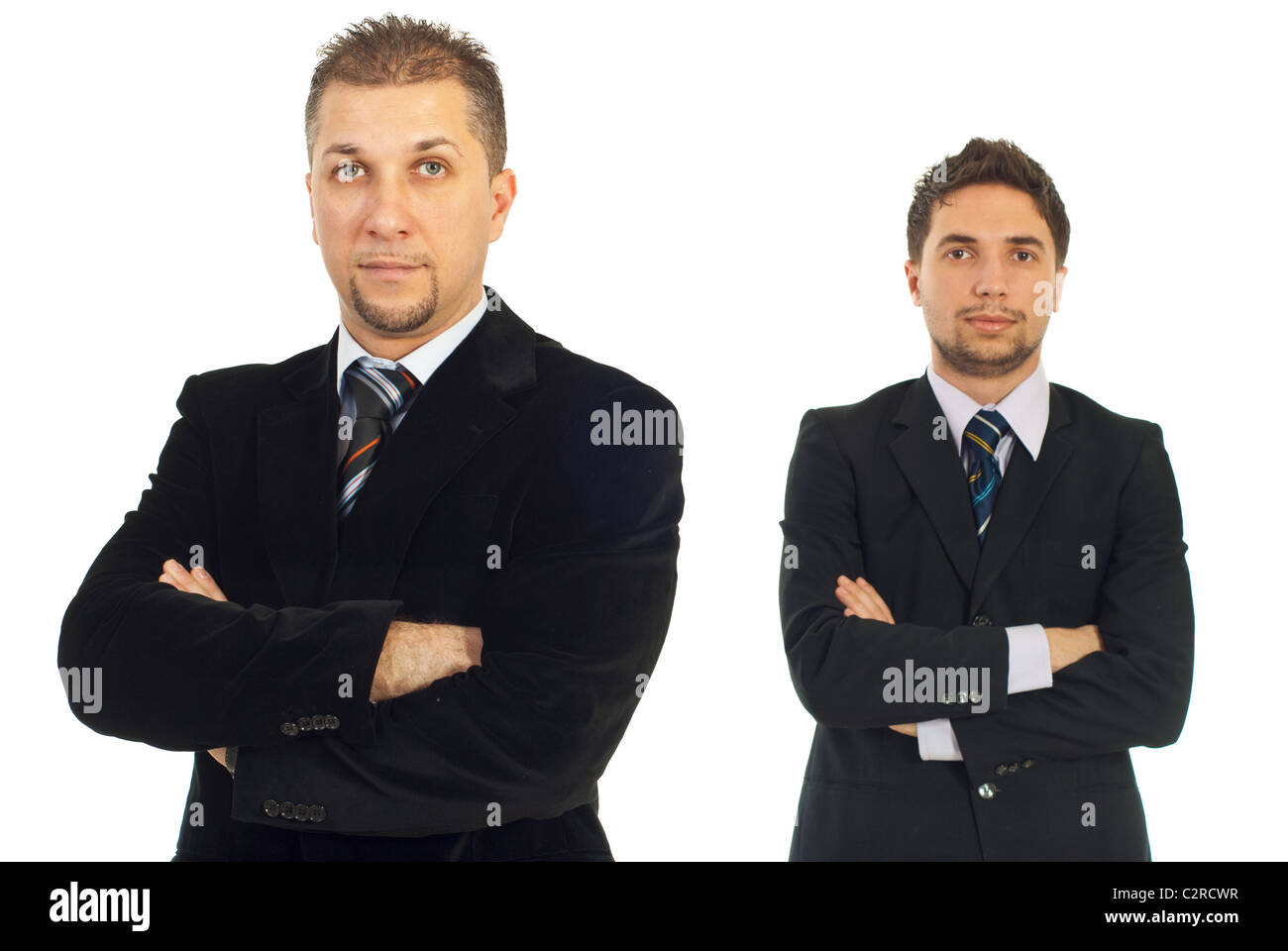 Mid adult man in front of camera standing croisés et son jeune collègue en arrière-plan Banque D'Images