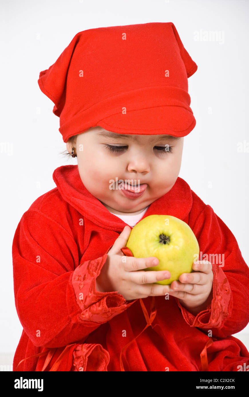 Vêtements bébé fille en rouge tenant une pomme dans ses mains et à la  recherche à la fruit de la luxure et de la langue comme elle dit Photo  Stock - Alamy
