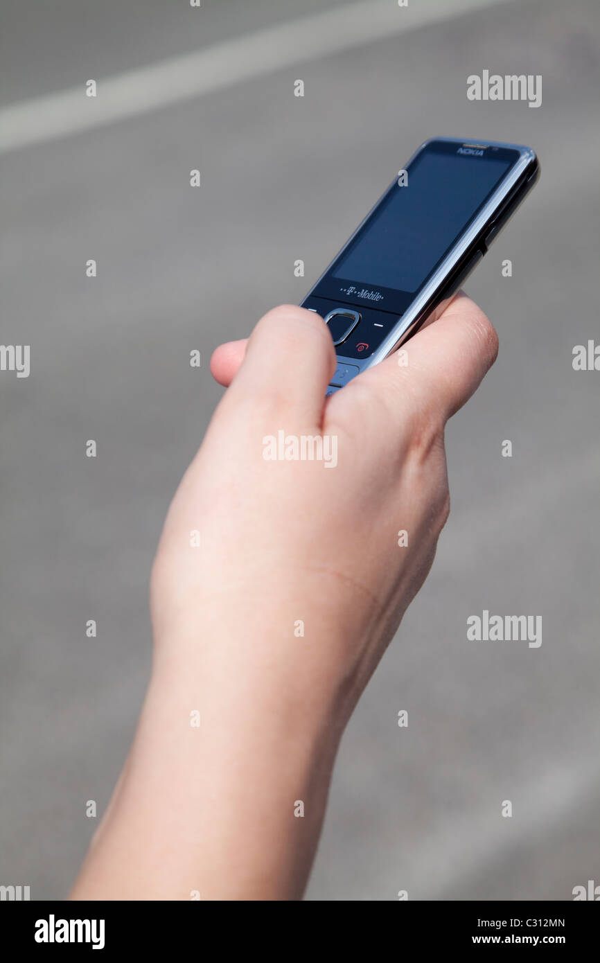Une jeune femme tenant son téléphone mobile alors que l'envoi d'un SMS Short Messaging service sms Angleterre Nottingham UK Banque D'Images