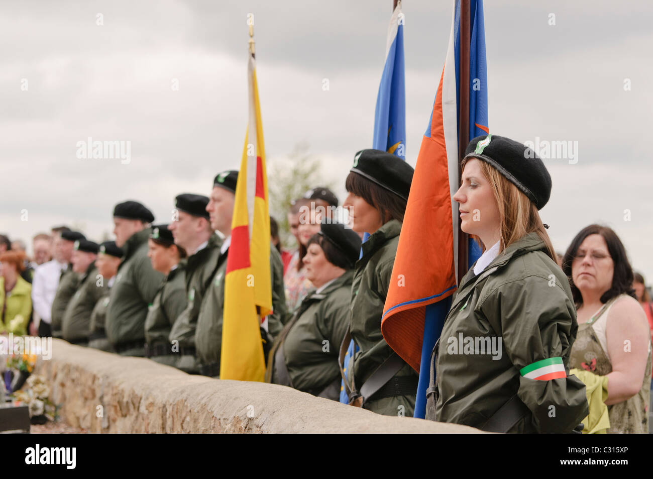 Belfast, Irlande du Nord. 24 avr 2011 - gens habillés en vêtements de style paramilitaire maintenez options que le Sinn Fein commémorer l'Insurrection de Pâques 1916 à la parcelle en républicaine d'Antrim Millfield cimetière. Banque D'Images