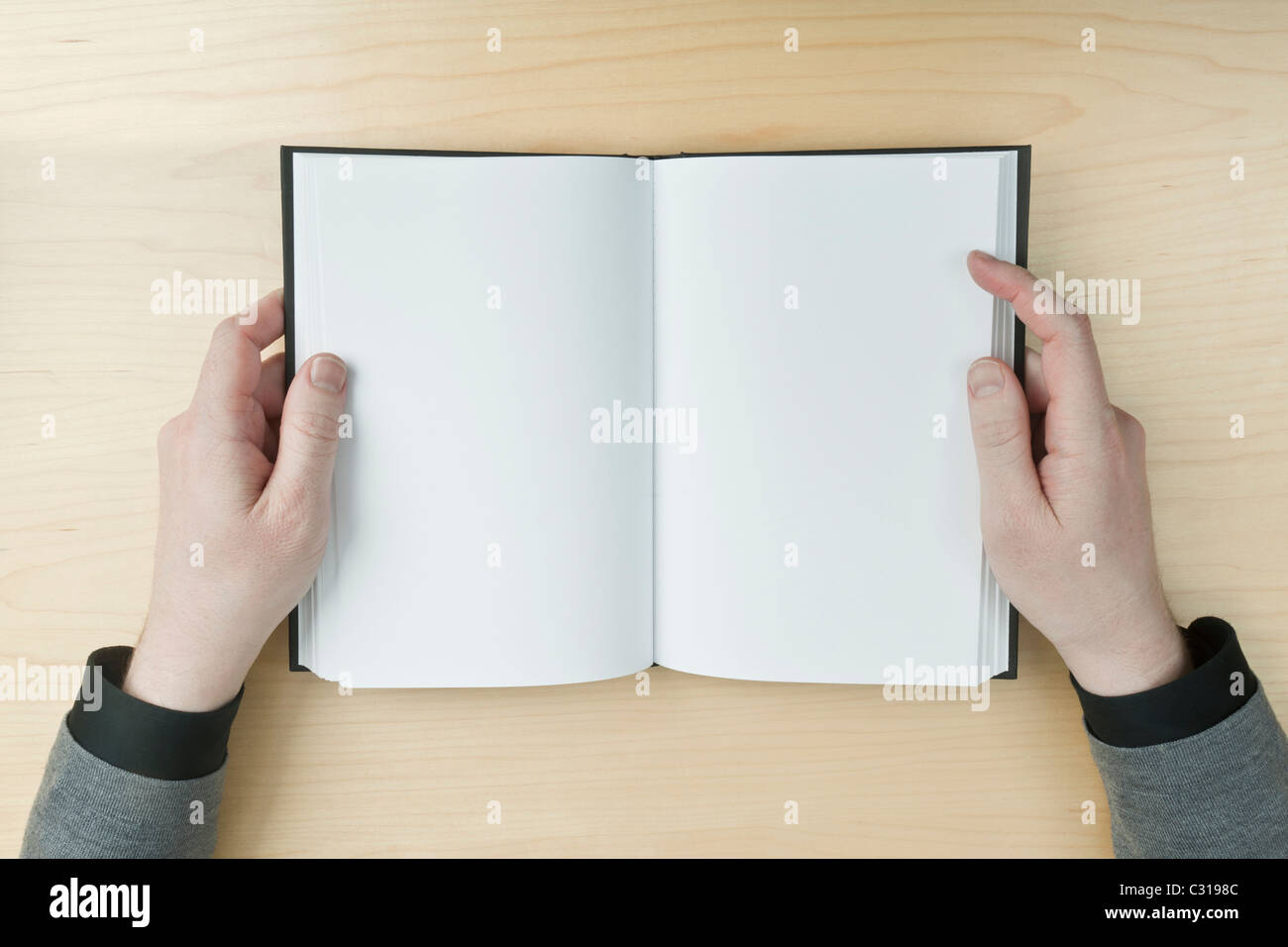 Jeune homme lisant un livre ouvert vide sur un bureau - insérer votre propre message. Banque D'Images