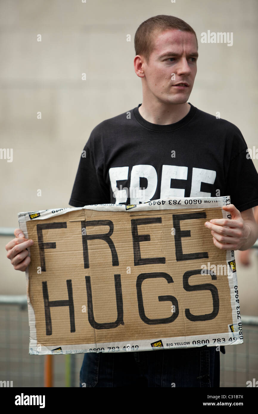 Portrait d'un jeune homme portant un panneau Free Hugs dans un lieu public, Londres, Angleterre, Royaume-Uni Banque D'Images