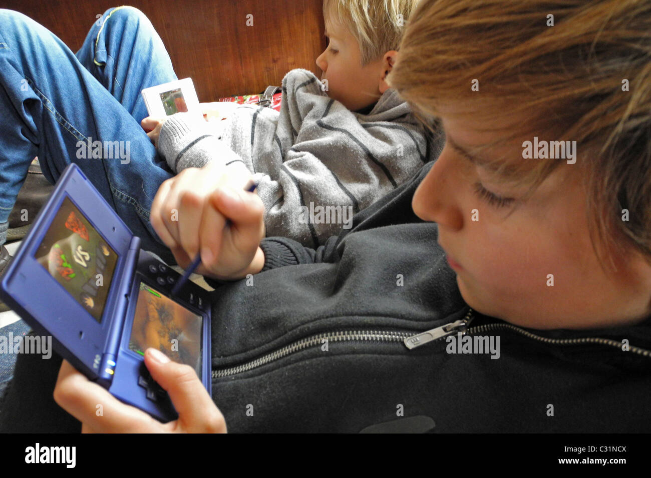 Les ENFANTS JOUER À DES JEUX VIDÉO (CONSOLE NINTENDO DS), CHACUN À SON Banque D'Images Les ENFANTS JOUER À DES JEUX VIDÉO (CONSOLE NINTENDO DS), CHACUN À SON Banque D'Images