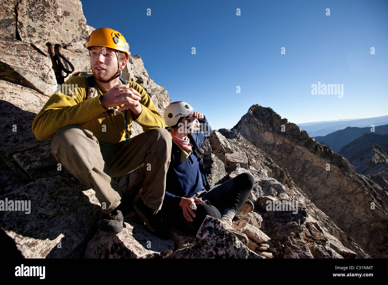 Deux jeunes gens assis sur une ligne de crête exposée en faisant une pause pendant que l'alpinisme. Banque D'Images