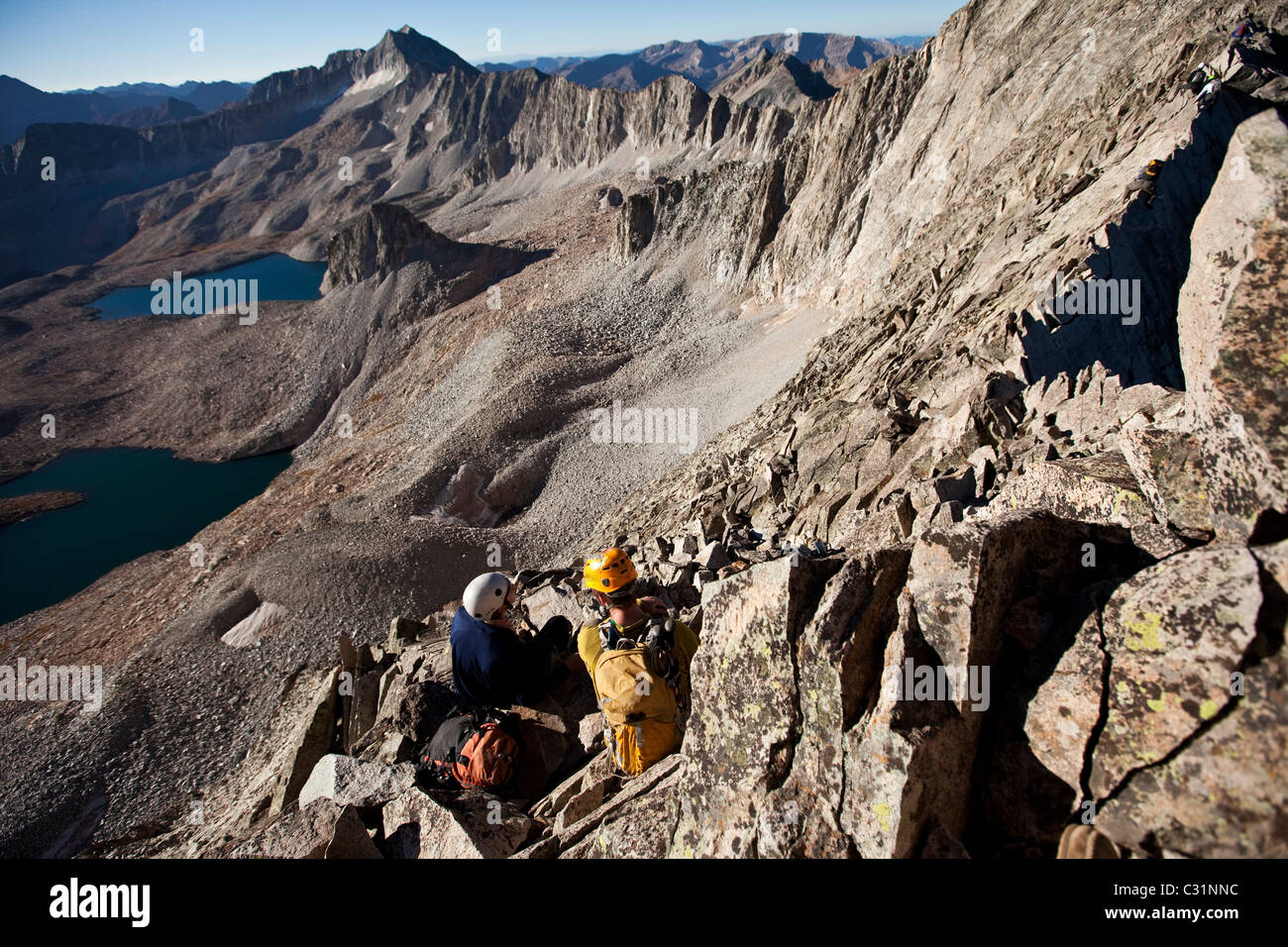 Deux jeunes gens assis sur une ligne de crête exposée en faisant une pause pendant que l'alpinisme. Banque D'Images