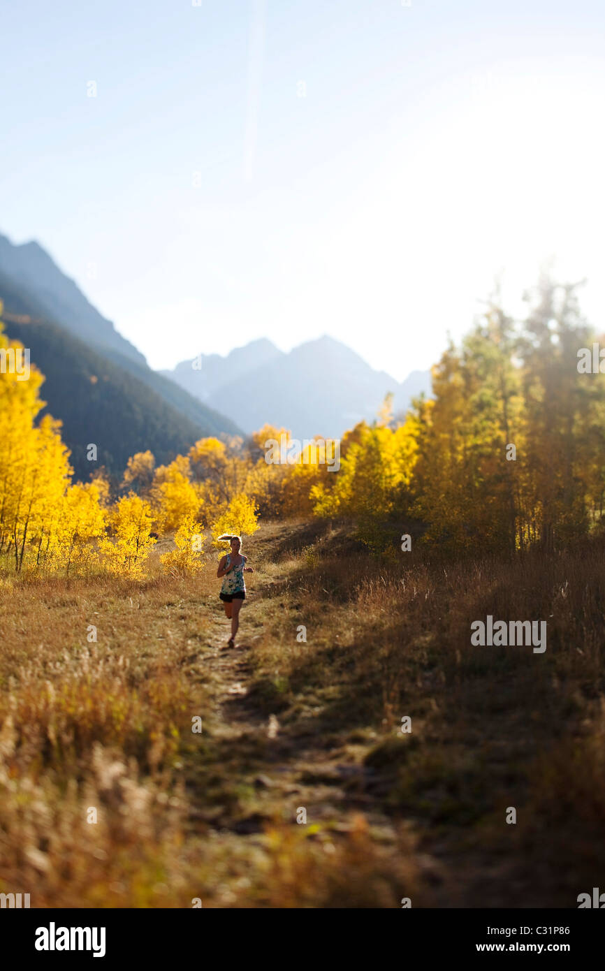Une jeune femme trail running dans les couleurs d'automne. Banque D'Images