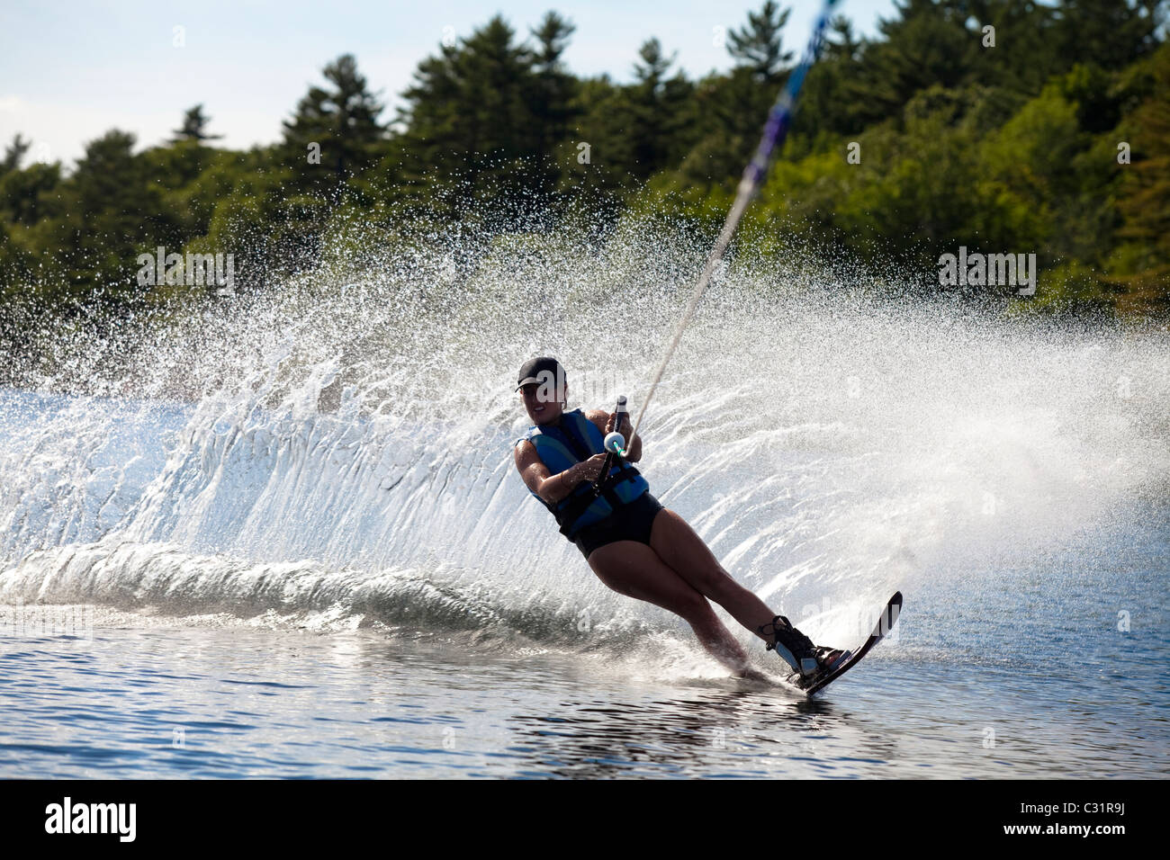 Une skieuse nautique déchire tour provoquant un énorme jet d'eau tandis que le ski sur le lac Cobbosseecontee près de Monmouth, Maine. Banque D'Images