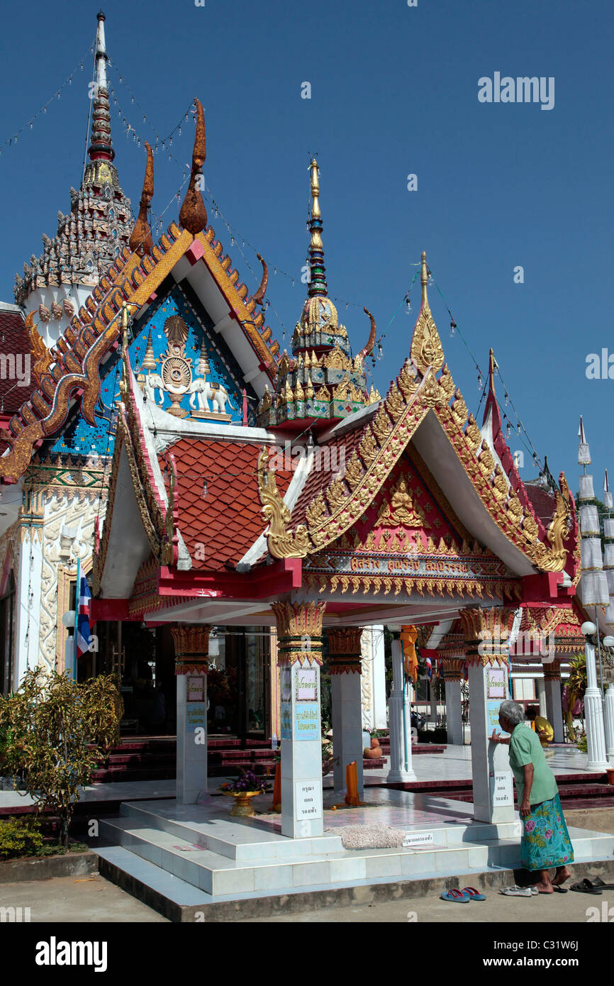 Vieille Femme PRISE DE SES CHAUSSURES À L'entrée du temple bouddhiste de BANG SAPHAN, Thailande, ASIE Banque D'Images