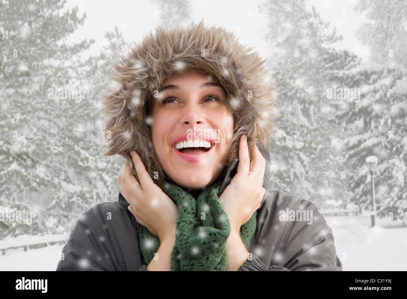 Mixed Race woman in fur hood à regarder la neige tomber Banque D'Images