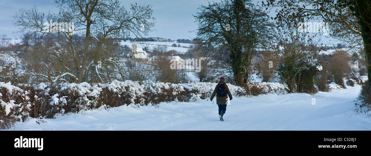 Lone walker le long couloir couvert de neige dans la vallée, Windrush, les Cotswolds Swinbrook Banque D'Images