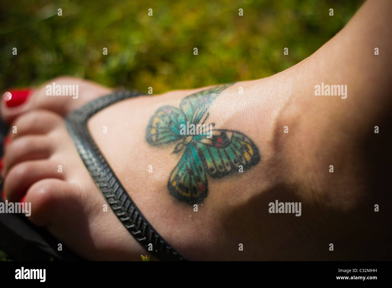 Tatouage papillon sur un pied de femme jeune Banque D'Images