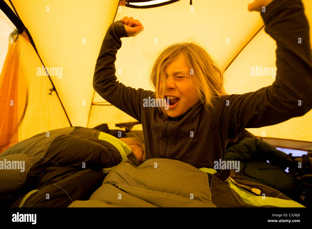 Un garçon se réveille dans sa tente en camping dans l'arrière-pays de la Californie. Banque D'Images