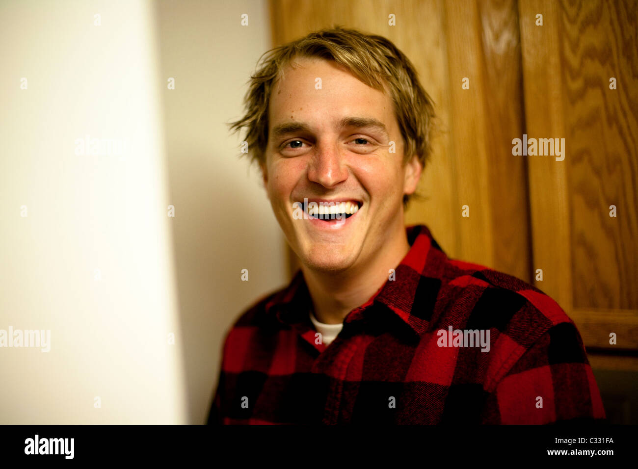 Un jeune homme portant une veste de flanelle rouge souriant à une caméra à Camarillo, Californie. Banque D'Images