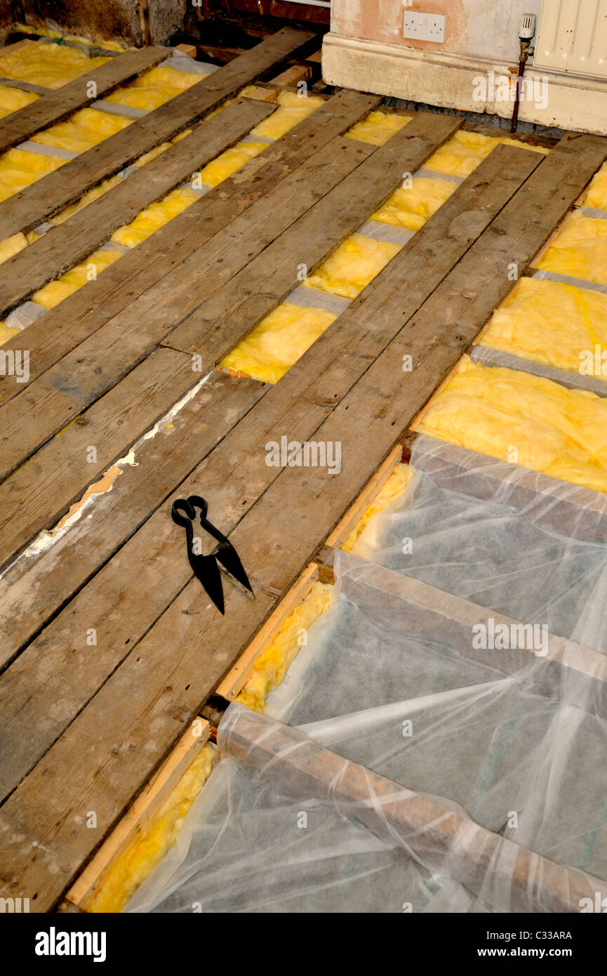 L'installation de l'isolant en fibre de verre sous plancher suspendu dans un vieux plancher en bois afin de réduire les pertes de chaleur Banque D'Images