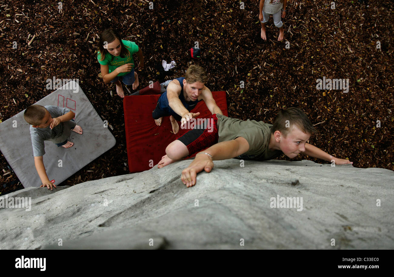 Jeune garçon enfant escalade bouldering pendaison route difficile à boulder rocher au-dessus de coffre crashpad high angle shot Banque D'Images