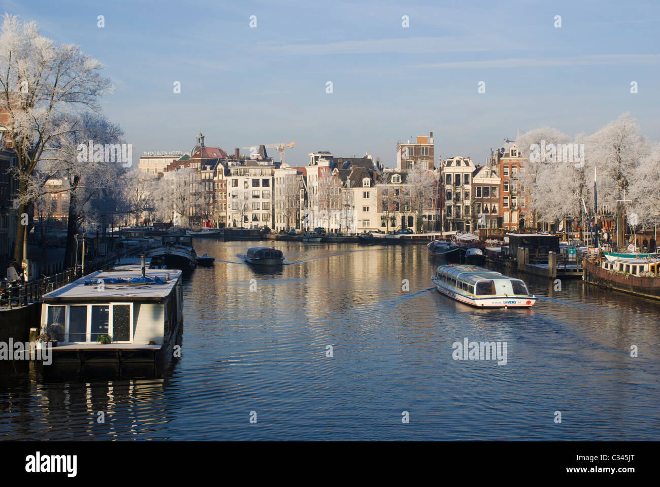 Des bateaux touristiques sur la rivière Amstel, dans une rue calme matin d'hiver à Amsterdam, aux Pays-Bas. Banque D'Images