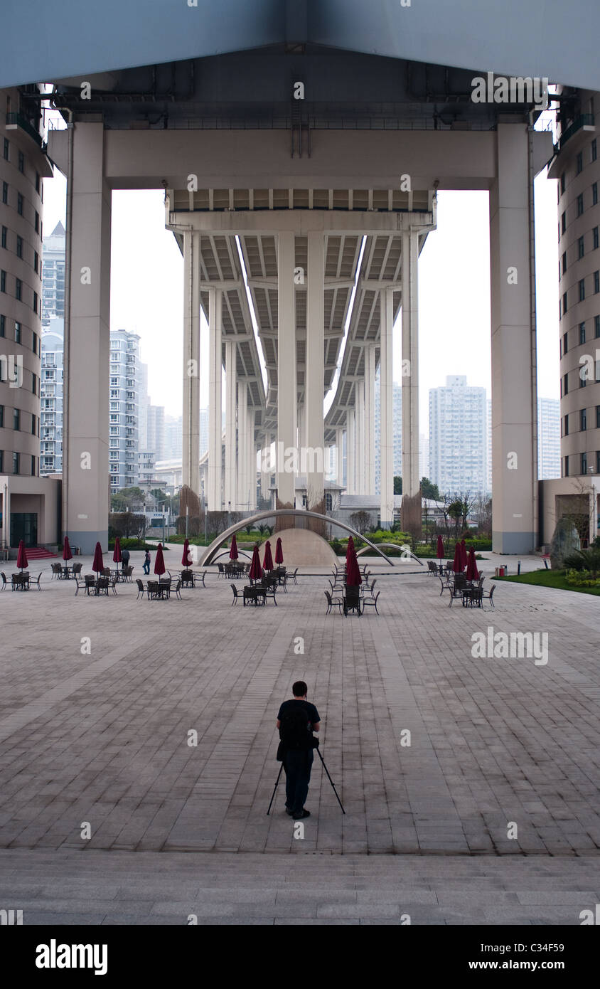 Un photographe se tient sous le pont Lupu à Shanghai, Chine, et est éclipsé par l'ampleur de celui-ci. Banque D'Images