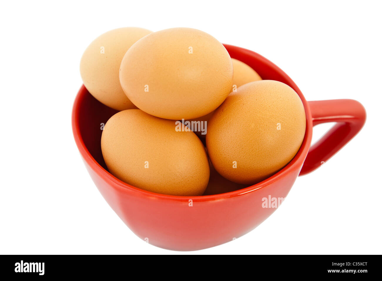 Brown oeufs dans un bol rouge sur fond blanc Banque D'Images