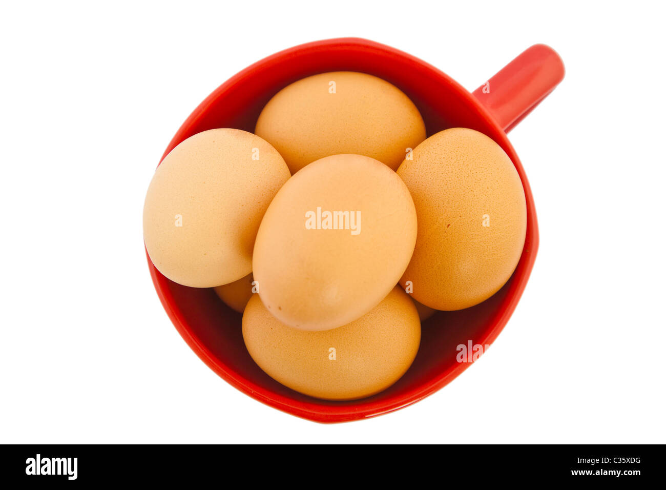 Brown oeufs dans un bol rouge sur fond blanc Banque D'Images