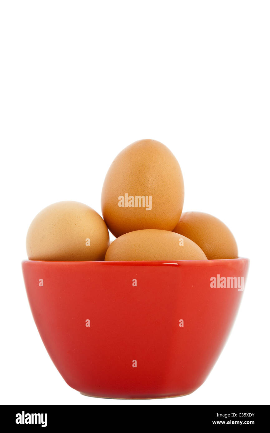 Brown oeufs dans un bol rouge sur fond blanc Banque D'Images