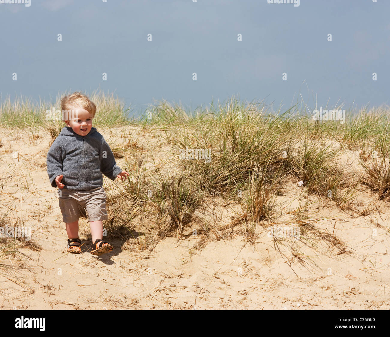 Un petit garçon jouant sur des dunes de sable Banque D'Images