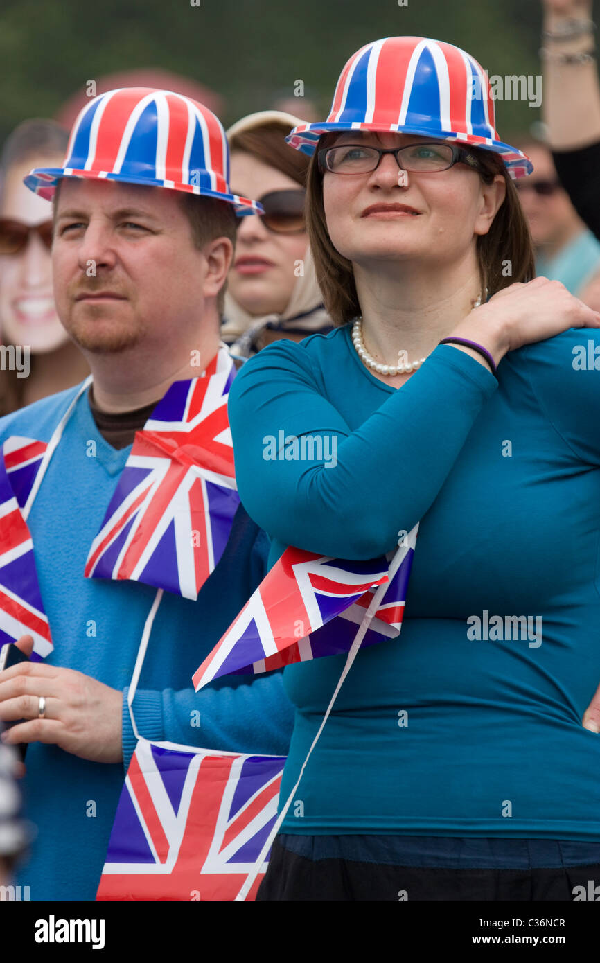 Les fêtards royaux de mariage célèbrent avec des chapeaux et des drapeaux union Jack regardant des écrans géants diffusant mariage à Hyde Park, Londres, Royaume-Uni Banque D'Images