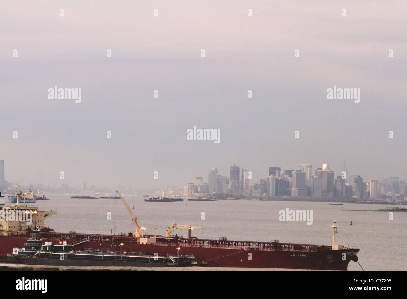 Voir l'île de Manhattan et Cargo crossing Hudson River pendant le coucher du soleil, New York City Banque D'Images