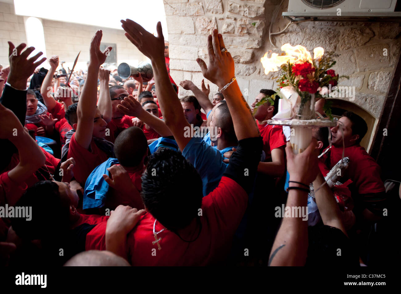 Avec des bougies allumées pendant le rituel du feu le jour avant Pâques, chrétien palestinien youth surge à travers les rues de Jérusalem. Banque D'Images