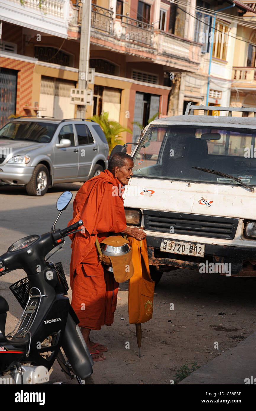 Personnes âgées Le moine bouddhiste la collecte de l'aumône dans une rue à Kampot, Cambodge Sud. Banque D'Images