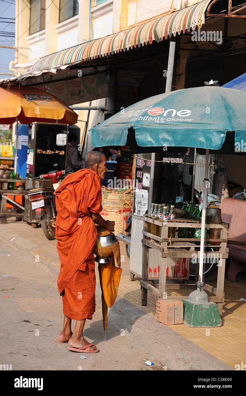 Personnes âgées Le moine bouddhiste la collecte de l'aumône dans une rue dans le sud de Kampot au Cambodge. Banque D'Images