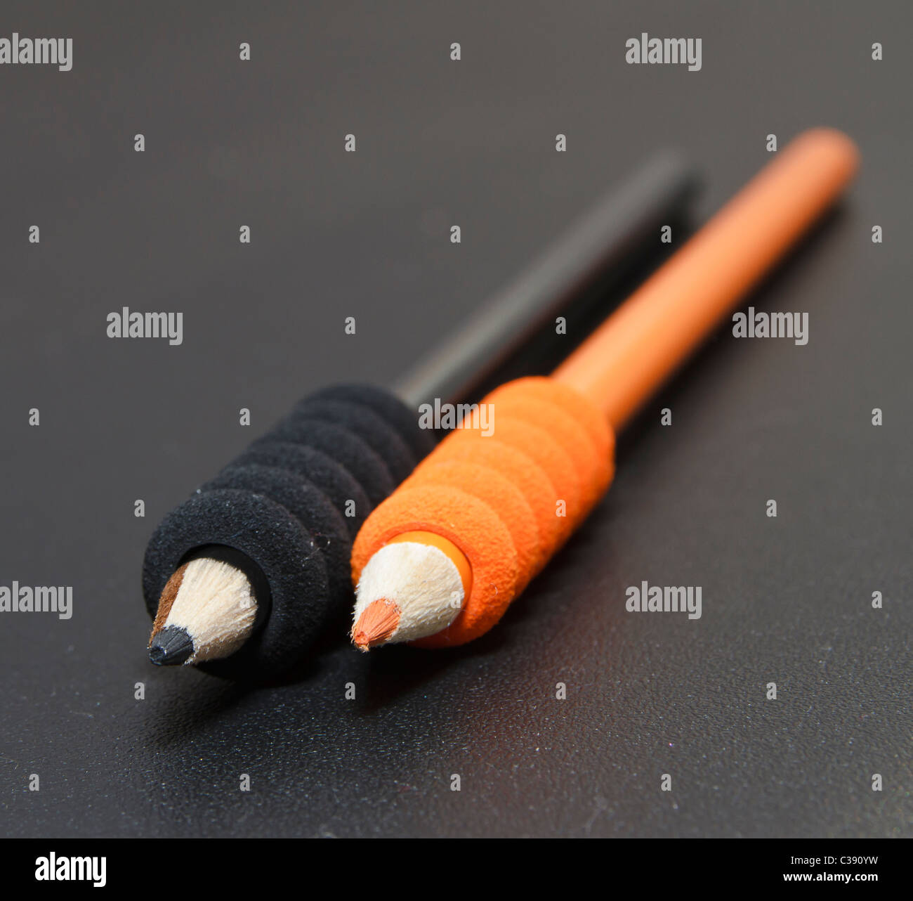 Crayons noir et orange sur un bureau noir Banque D'Images