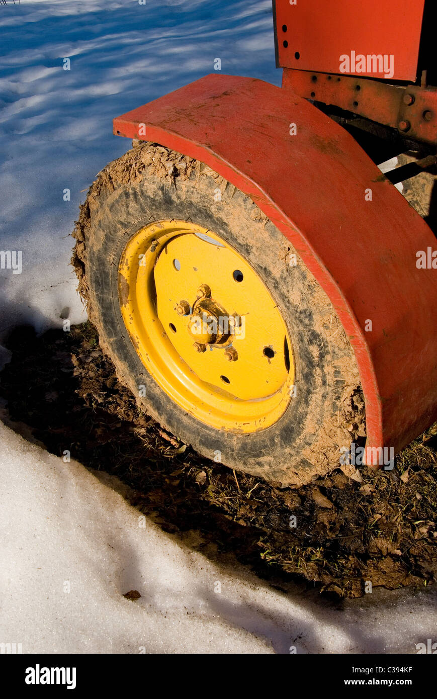 Fragment de l'ancienne roue du tracteur jaune couverte de boue. Banque D'Images